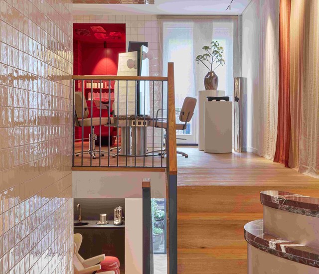A stairway ascending to a room featuring a vibrant red wall, creating a striking visual contrast at a beauty salon in Amsterdam.